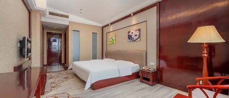 A hotel room with a bed, bedside table, lamp, and a television.