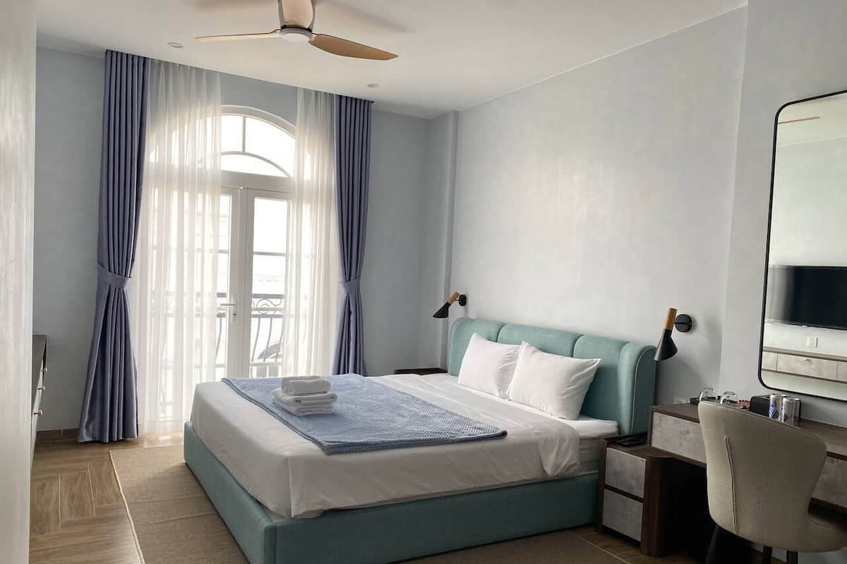 A bedroom with a bed, a desk, and a chair.