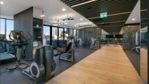 Ein modernes Fitnessstudio mit Cardiogeräten, Kraftstationen und Holzboden.