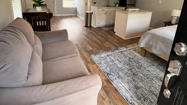 A compact living space with a sofa, a rug, a kitchen area, and a dining table. - Casa Hornitos/Beautiful Cottage 8 min from lake (Livingston)