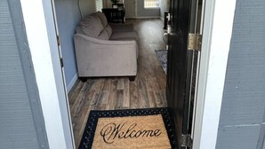 A hallway with a sofa, a door, and a welcome mat. - Casa Hornitos/Beautiful Cottage 8 min from lake (Livingston)