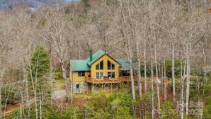 Une cabane en bois, surmontée d’un toit vert et entourée d’arbres, située dans une région montagneuse.