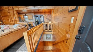 Un intérieur en bois avec un escalier menant à un deuxième étage, un canapé et un coin cuisine.