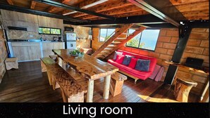 Ein Wohnzimmer mit einem Holzesstisch, Bänken, einem roten Sofa und einer Treppe zu einer oberen Ebene.