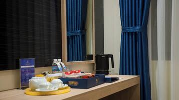 A hotel room with a wooden vanity, a mirror, a coffee maker, and a small seating area.