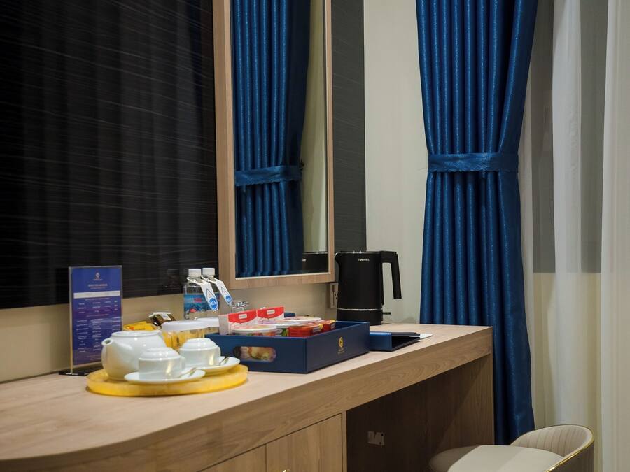 A hotel room with a wooden vanity, a mirror, a coffee maker, and a small seating area.