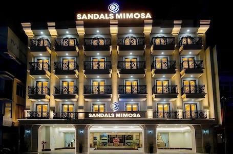 A multi-story hotel with balconies, a prominent sign, and a well-lit entrance.