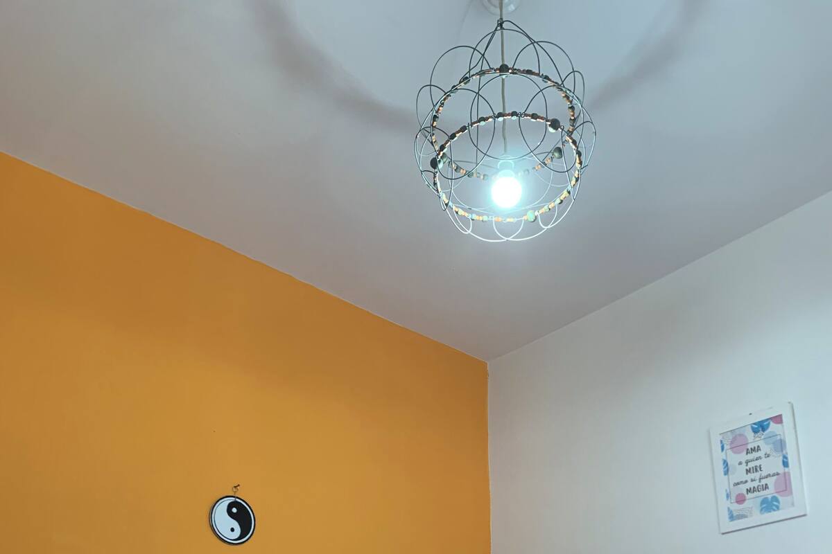 Ett sovrum med en säng, en vägg prydd med en yin-yang-symbol, en affisch och en unik taklampa.