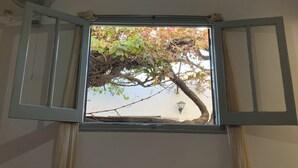 A bedroom with a bed, a window with an open frame, a ceiling fan, and a hanging light fixture. - Hostal de Luz (Capilla del Monte)
