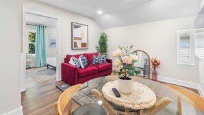 A modern living room with a red sofa, a glass coffee table, and a potted plant.