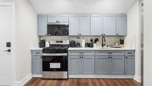 A modern kitchen with grey cabinets, a stainless steel stove, and a microwave.