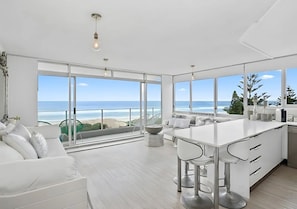 A modern kitchen with a large island, white cabinetry, and a view of the beach. - Ocean Views in the Gold Coast w/ Pool and Balcony (Gold Coast)
