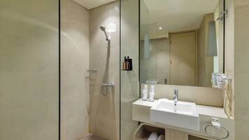 Un baño moderno con cabina de ducha de vidrio, un lavabo blanco y un espejo grande.