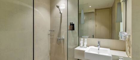 A modern bathroom with a glass shower enclosure, a white sink, and a large mirror.