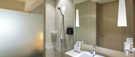 A modern bathroom with a glass-enclosed shower, a white sink, and a large mirror.