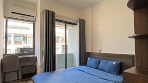 A hotel room with a bed, a desk, and a chair. - Zeus Living - 7C Downtown By Feet (Ho Chi Minh City)