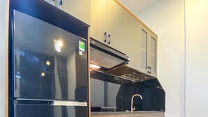 A modern kitchen with a black refrigerator, wooden cabinets, and a built-in oven. - Zeus Living - 7C Downtown By Feet (Ho Chi Minh City)