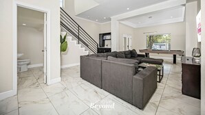 A spacious living room with a sectional sofa, a staircase, and a pool table. - Sprawling Home w/ Rooftop Spot (San Antonio)