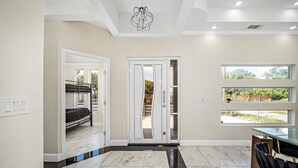 A modern interior with a dining area, a staircase, and a view through a glass door. - Sprawling Home w/ Rooftop Spot (San Antonio)