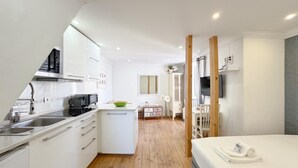 A compact hotel room with a kitchenette, a bed, a small dining area, and a bathroom. - Comfort in the heart of Alfama (Lisboa)