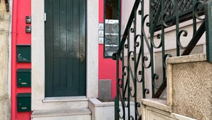A black door with a brass knocker, a red wall, and a set of green mailboxes. - Comfort in the heart of Alfama (Lisboa)