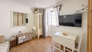 A bedroom with a bed, a dresser, a desk with a chair, a TV, and a window with curtains. - Comfort in the heart of Alfama (Lisboa)