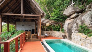 A wooden deck with a pool, lounge chairs, and a stone wall. - Koh Tao Villas (Koh Tao)