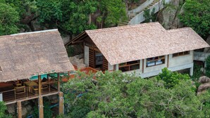 A traditional wooden house with a thatched roof, surrounded by lush greenery and a stone staircase. - Koh Tao Villas (Koh Tao)