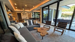 A modern living room with a sectional sofa, two wooden chairs, and a coffee table. - Casa Pipeline: Jungle Villa, Pool, Sleeps 14 (Nosara)