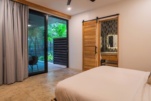 Un dormitorio con cama, una puerta corrediza de vidrio que da a un balcón y un armario de madera.