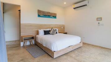 Een moderne slaapkamer met een houten bed, een plafondventilator, een airconditioner en een schilderij aan de muur.