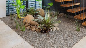 A modern staircase with wooden steps and metal railings, surrounded by plants and rocks. - Casa Pipeline: Jungle Villa, Pool, Sleeps 14 (Nosara)