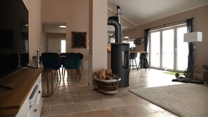 Uma sala de estar ampla com lareira, mesa de jantar e cadeiras.