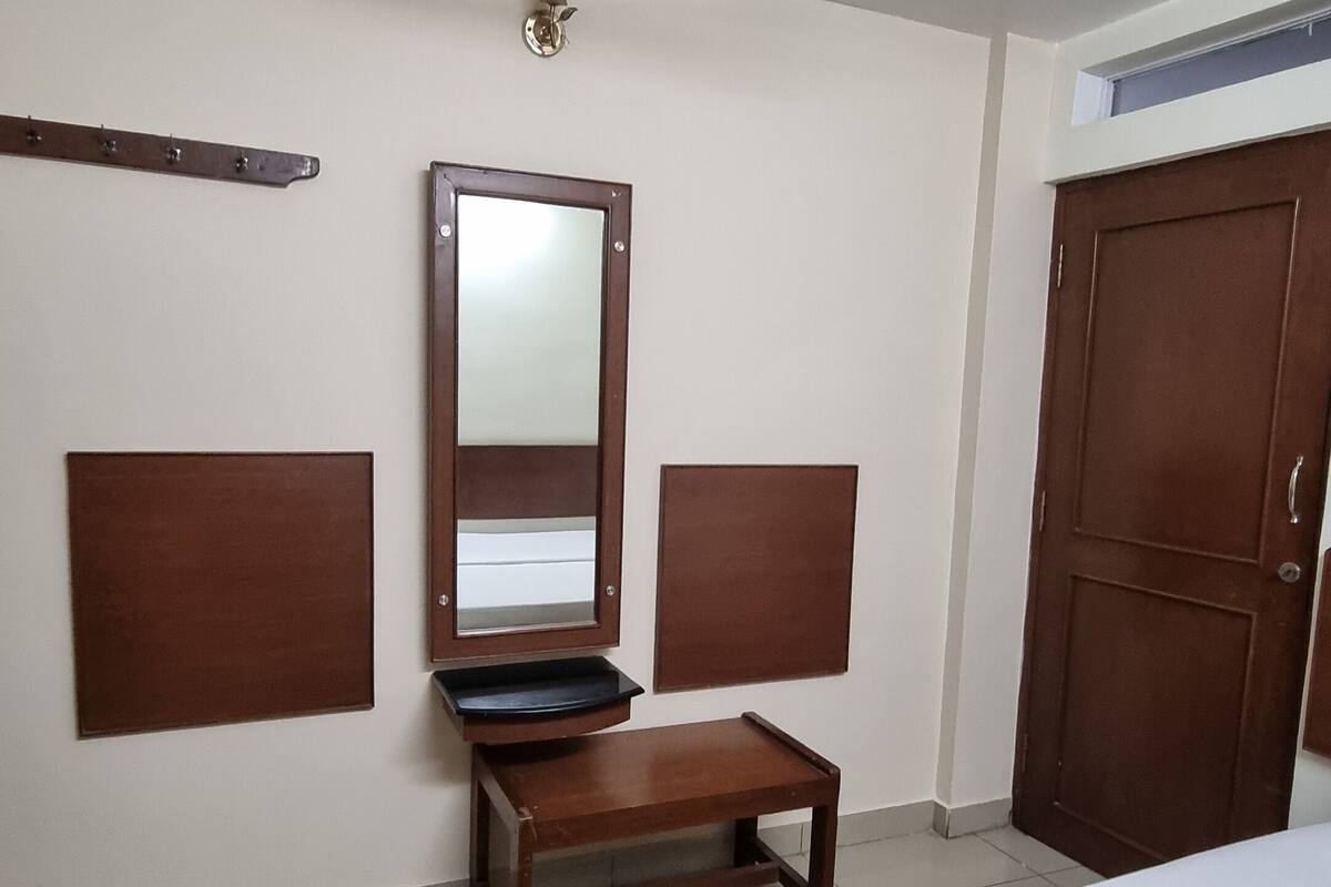 A hotel room with a bed, a wooden bench, a mirror, and a wardrobe.