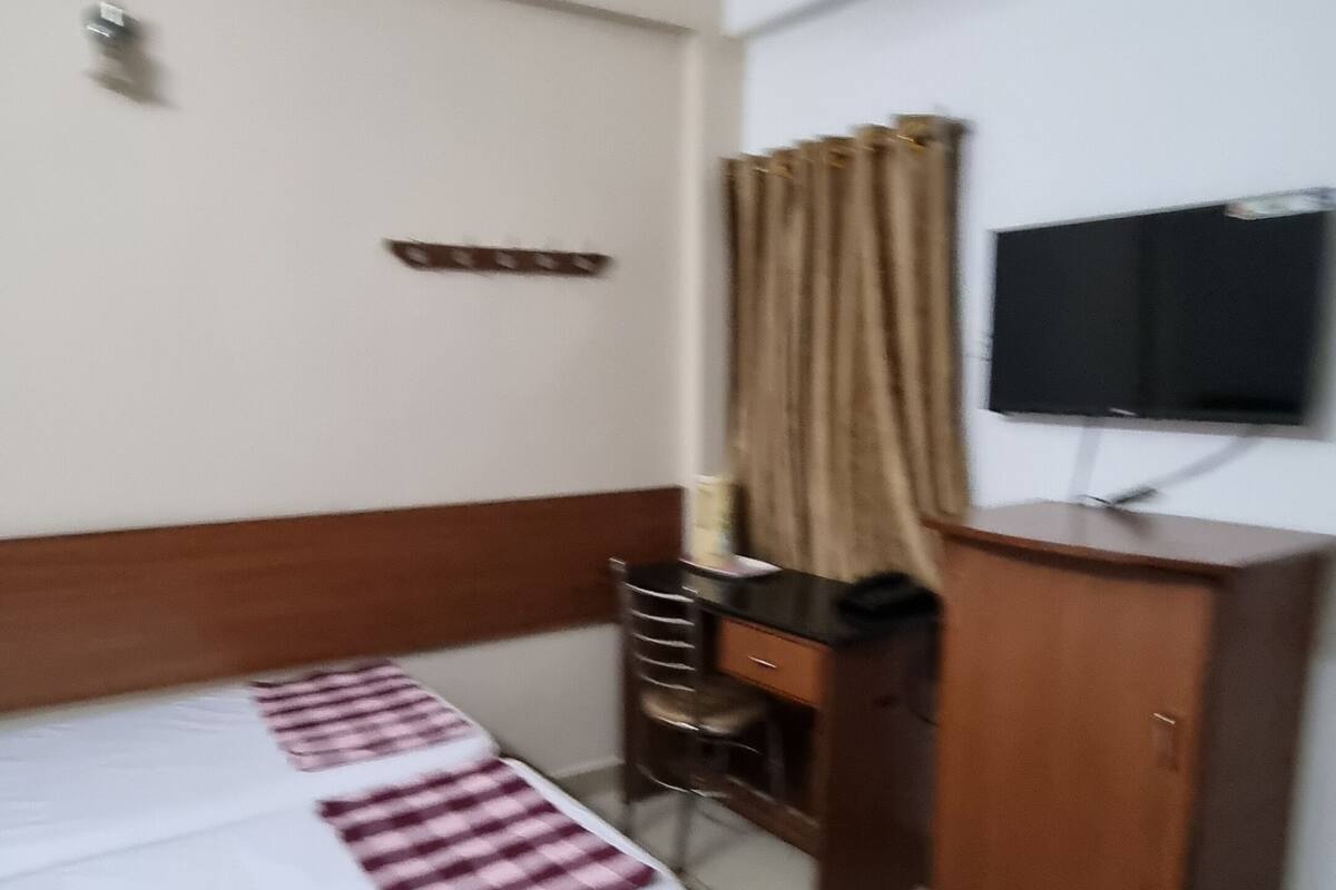 A hotel room with a bed, a desk, a television, and a ceiling fan.