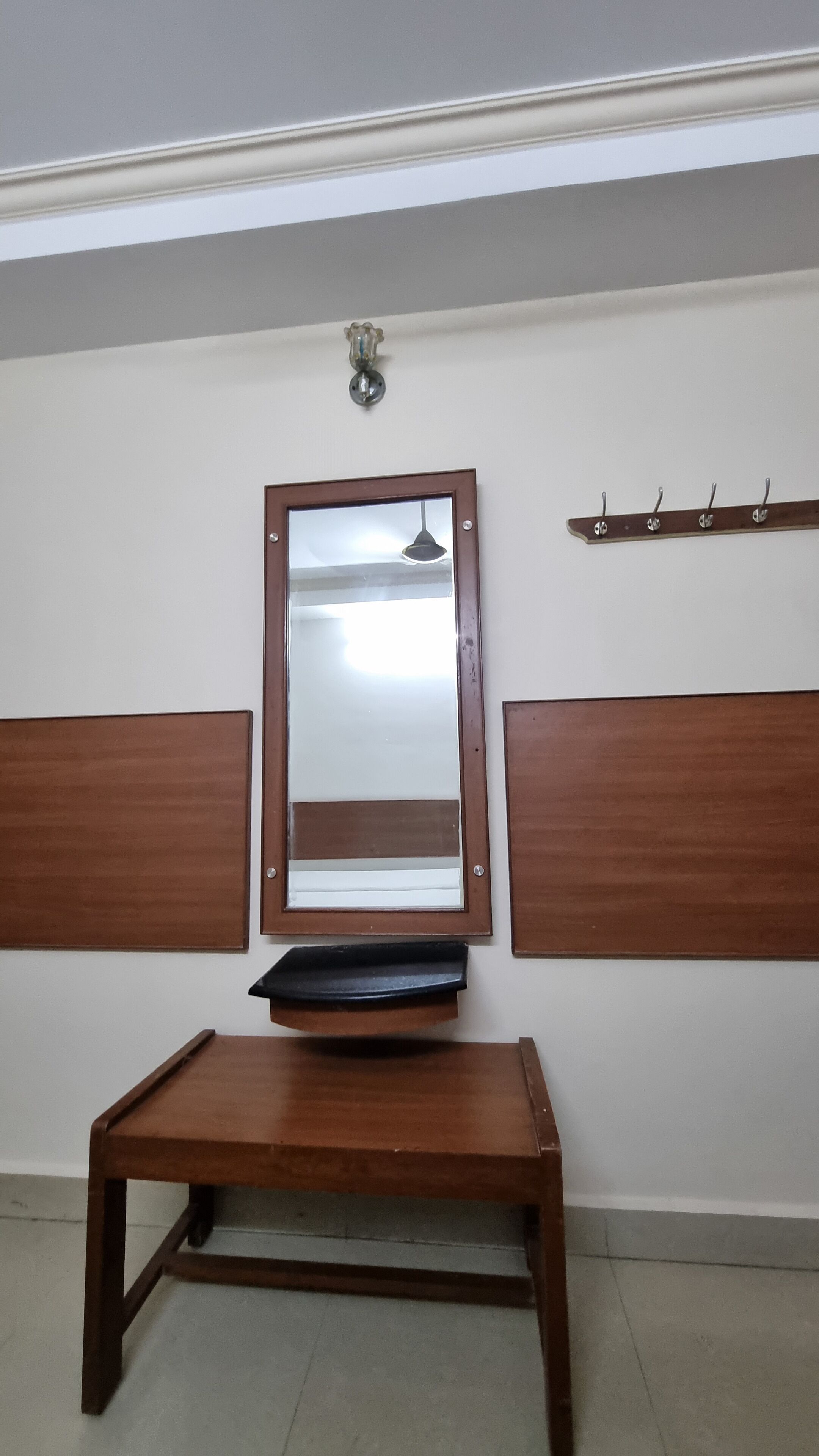 Ein Zimmer mit einer Holzbank, einem Spiegel und einem Kleiderständer.