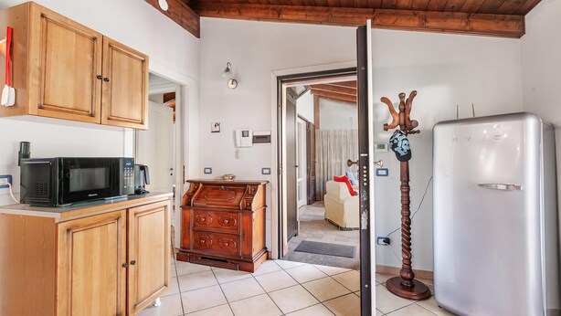 A kitchen with wooden cabinets, a microwave, a coffee maker, and a refrigerator. - Casa Rolè (Dormelletto)