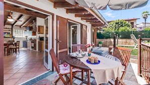 Un patio con una mesa lista para comer, una silla de madera y vistas a la cocina y al jardín.