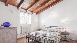 A bedroom with a bed, a nightstand, a dresser, a window, and a radiator. - Casa Rolè (Dormelletto)