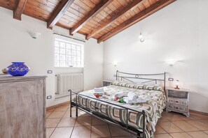 Ein Schlafzimmer mit Bett, Nachttisch, Kommode, Fenster und Heizkörper.