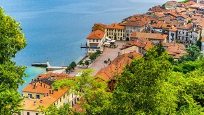 Un pueblo costero con edificios históricos, un paseo marítimo y abundante vegetación.