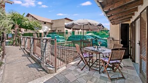 Un patio al aire libre con una mesa, sillas, una sombrilla y vista a una piscina.