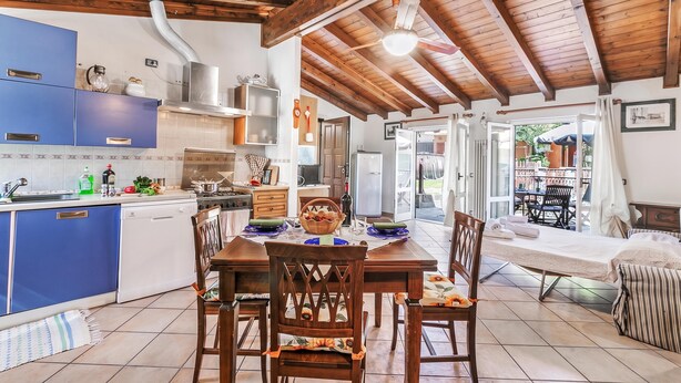 Una cocina con armarios azules, una mesa de comedor con sillas y vistas a un patio exterior.