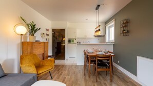 Un espacio habitable compacto con zona de comedor, un sofá, una mesita y una planta.