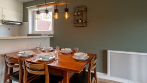 Comedor con una mesa de madera dispuesta para cuatro personas, rodeado de sillas.