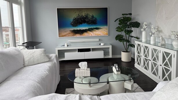 A modern living room with a large flat-screen TV, white furniture, a glass coffee table, and a potted plant. - Premier Host • Lux 2BR Pickering Retreat • AC, WiFi & Free Parking (Pickering)