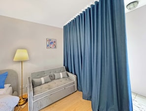 A modern bedroom with a grey sofa, a floor lamp, and a large window with blue curtains. - MetaWise 1Bed Next to ICC Darling Harbour 154 (Sydney)