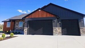 Una casa de dos pisos con fachada de piedra, sección superior de madera y un garaje gris oscuro.