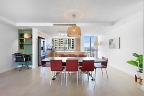 A modern kitchen with a large island, red chairs, and a hanging light fixture.