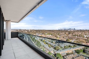 A balcony with a city view, including a distant skyline and residential area.